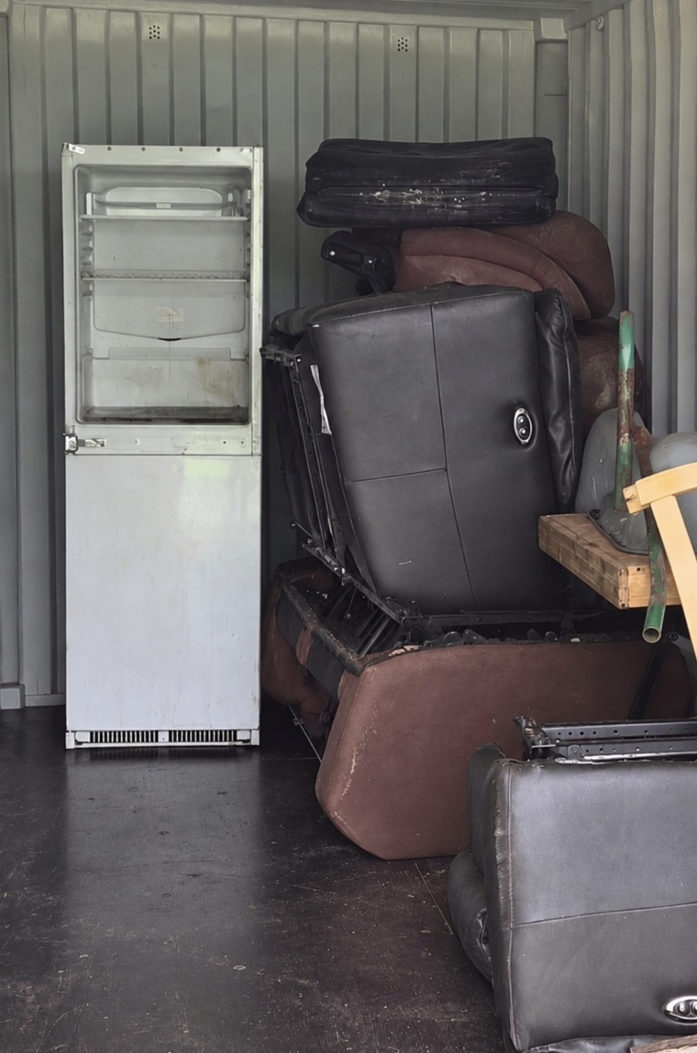 Used fridge freezer and bulky upholstered furniture awaiting disposal