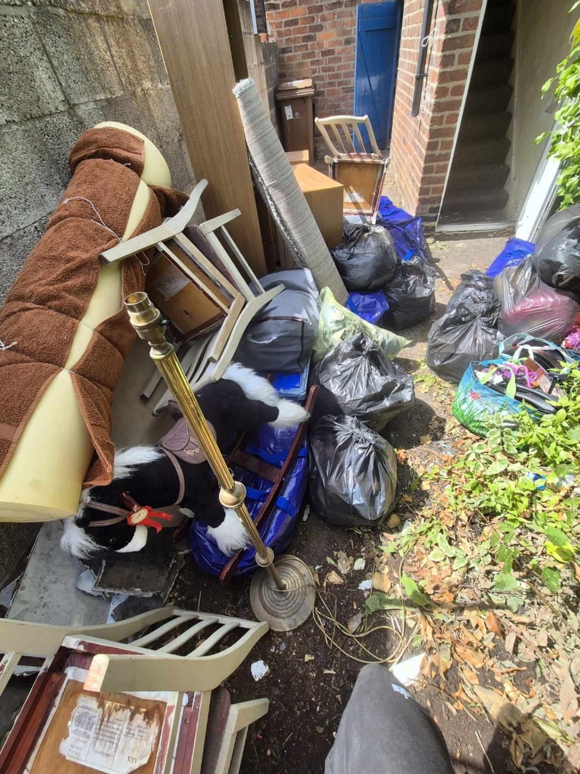 Outdoor furniture, rolled carpet and bagged rubbish ready for garden clearance